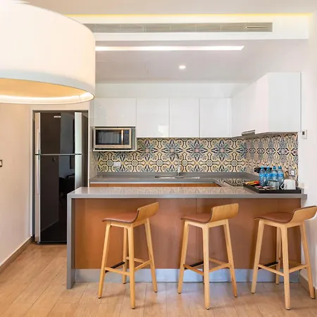 The Fives Beach Hotel & Residences - All Senses Inclusive Playa del Carmen Exterior photo The photo shows a modern kitchen area, likely in a hotel or apartment, with a sleek and inviting design. The kitchen features white upper cabinets and a light grey countertop. A backsplash with a beautiful patterned tile design in shades of blue, gre