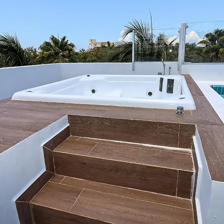 The Fives Beach Hotel & Residences - All Senses Inclusive Playa del Carmen Exterior photo The photo shows a luxurious outdoor space featuring a hot tub and a swimming pool. The hot tub is built into a raised wooden deck, surrounded by white tiled walls. There are steps leading down from the deck to the pool area. The pool has a colorful t