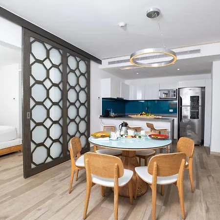 The Fives Beach Hotel & Residences - All Senses Inclusive Playa del Carmen Exterior photo The photo captures a bright and modern hotel suite or apartment. The main focus is a round dining table with a light blue glass top, surrounded by four light wooden chairs with white seats. The table is set with tableware, including plates, bowls, gl