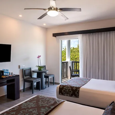 The Fives Beach Hotel & Residences - All Senses Inclusive Playa del Carmen Exterior photo The photo shows a brightly lit hotel room with a simple, modern aesthetic. The room is decorated in neutral tones of white and gray, with accents of brown and green. 

The main features of the room are two double beds, one of which is partially visib