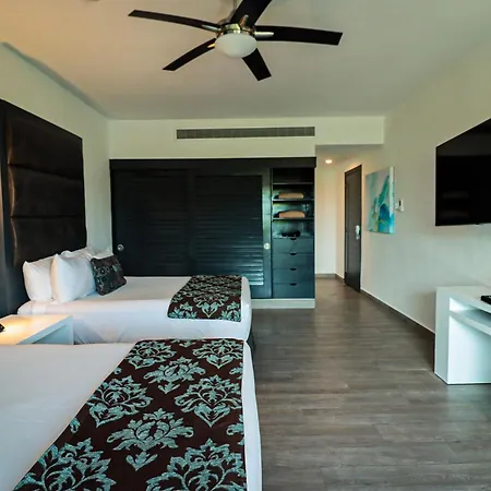 The Fives Beach Hotel & Residences - All Senses Inclusive Playa del Carmen Exterior photo The photo shows a well-lit hotel room with a modern and comfortable ambiance. The room features two double beds with white linens and decorative bed runners in a dark maroon and teal floral pattern. Each bed has multiple pillows, including some with 