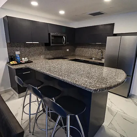 The Fives Beach Hotel & Residences - All Senses Inclusive Playa del Carmen Exterior photo The photo shows a modern kitchen with a sleek, contemporary design. The kitchen features dark gray cabinetry, a speckled granite countertop that extends to create a breakfast bar with seating. 

The breakfast bar is surrounded by three black bar stoo