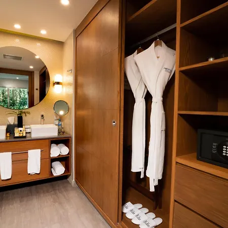 The Fives Beach Hotel & Residences - All Senses Inclusive Playa del Carmen Exterior photo The photo shows a well-appointed hotel bathroom with a focus on a wooden wardrobe. The bathroom has warm, inviting lighting, including sconces on either side of a large, round mirror above a double vanity. The vanity features two white rectangular si
