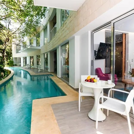 The Fives Beach Hotel & Residences - All Senses Inclusive Playa del Carmen Exterior photo The photo shows a luxurious resort setting with a stunning infinity pool as the main focus. The pool has a beautiful turquoise color and curves gracefully, seemingly blending into the lush green tropical vegetation surrounding it. 

Adjacent to the p
