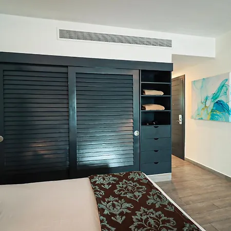 The Fives Beach Hotel & Residences - All Senses Inclusive Playa del Carmen Room photo This is an interior photograph of a modern, clean, and well-lit room, likely a bedroom or part of a studio apartment.

The focal point of the image is a large, dark-colored built-in wardrobe system. This system features two large, sliding doors with 